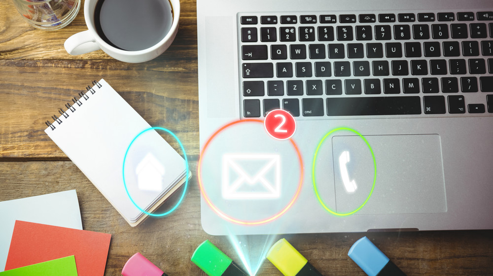 Composite image of laptop, notebook and coffee on a desk with contact icons